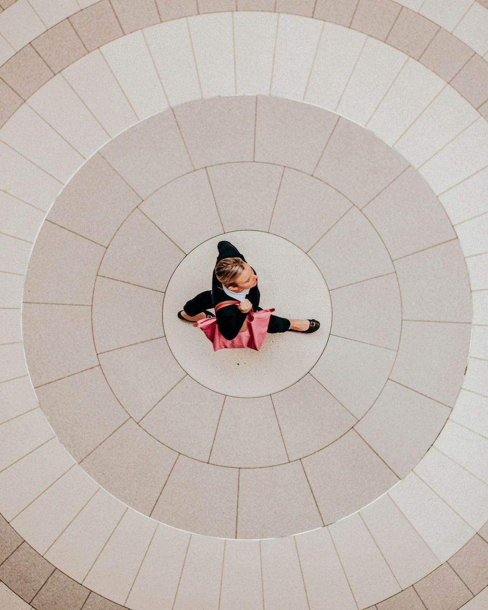 A professional standing at the centre of concentric circles, seen from above